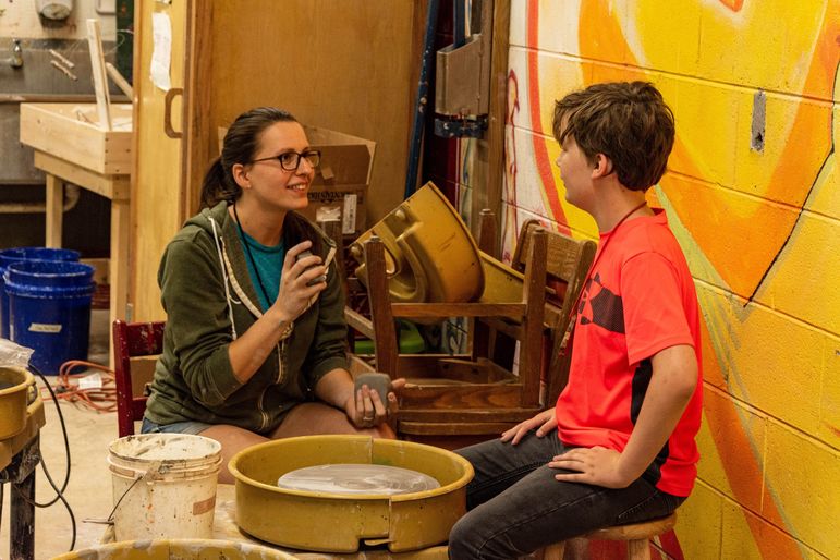 Keira instructing one of the boys in her pottery class