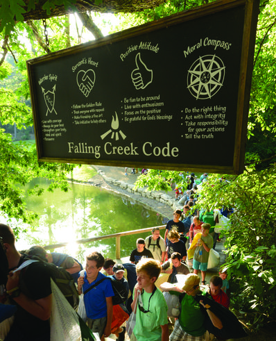 Campers walk under The Code sign during the day.